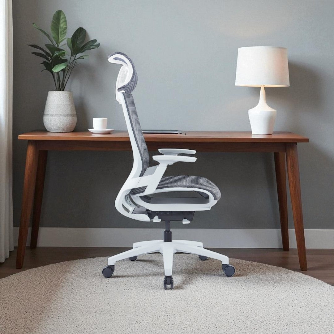 White office chair in front of a wooden desk with a plant and lamp.