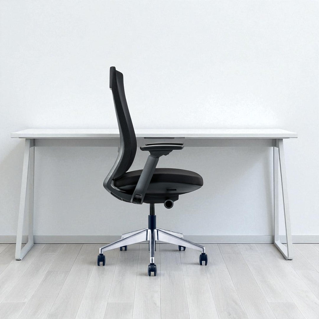 Black office chair in front of a white desk against a white wall.