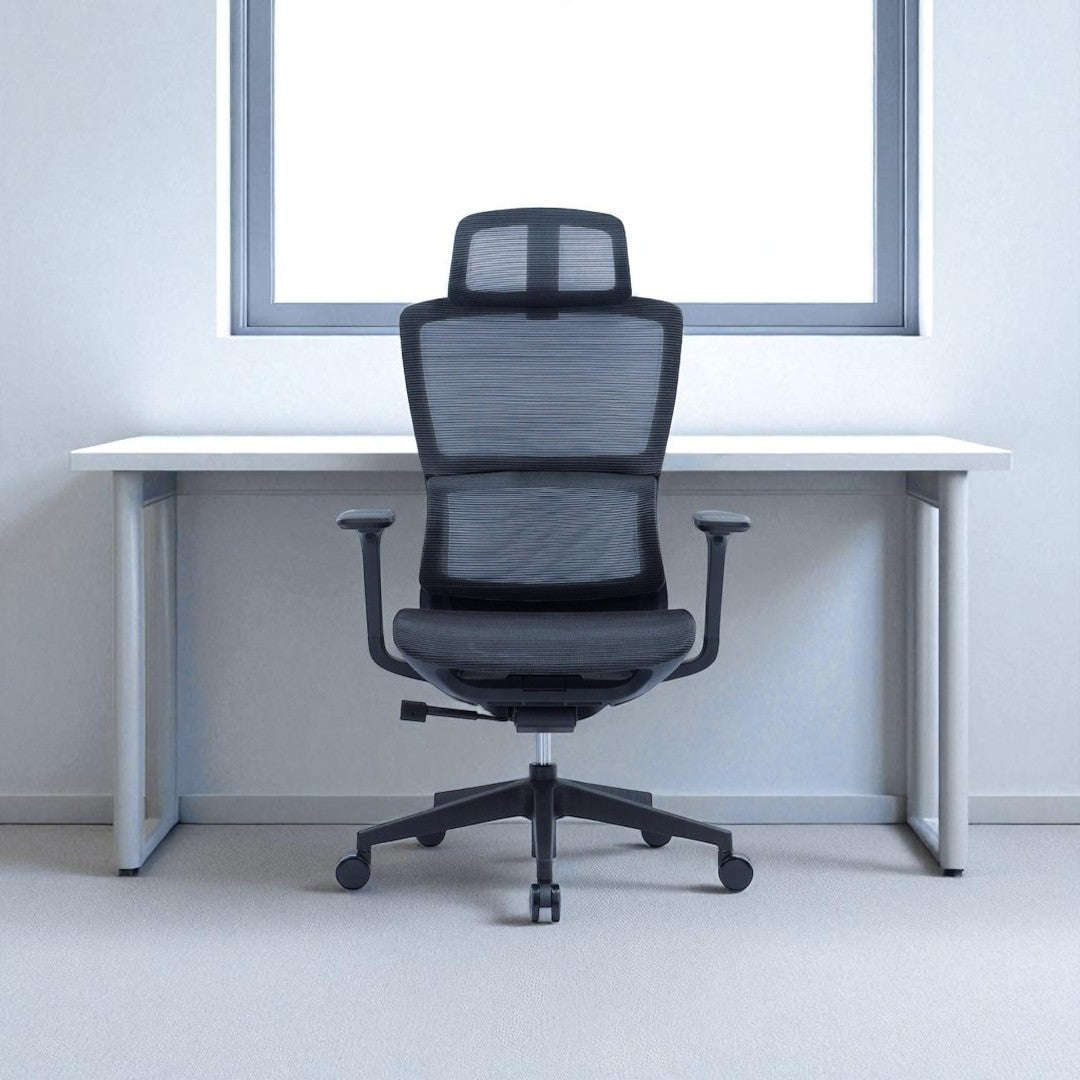 Black office chair in front of a white desk with a light gray wall and window in the background
