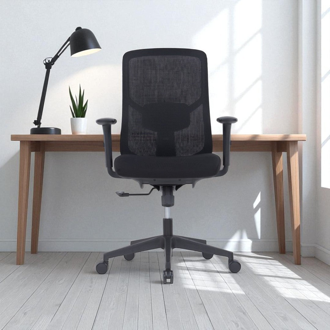 Black office chair in a bright room with a wooden desk and lamp.